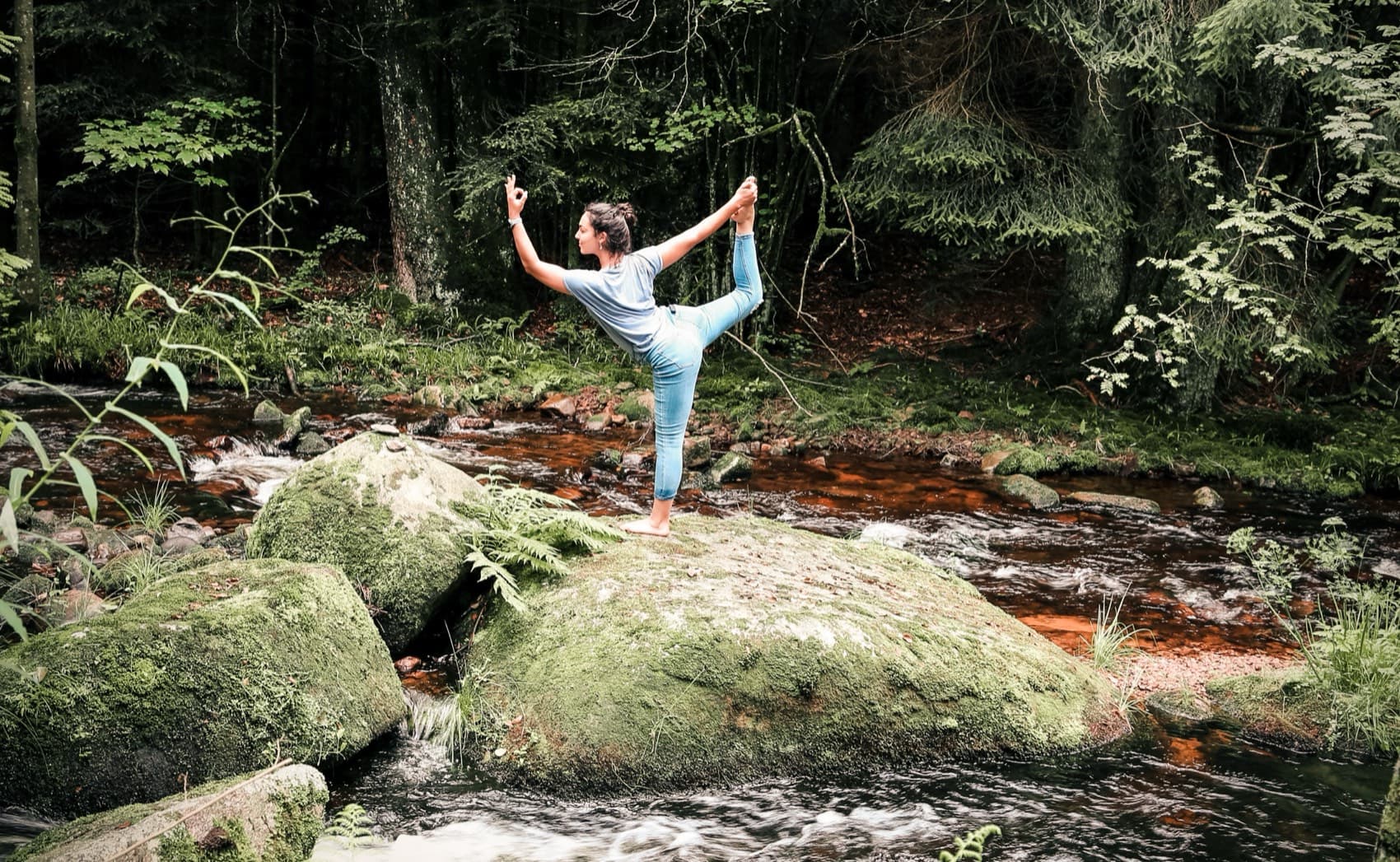 Sophie in der Tänzer-Pose auf einem Felsen an einem Waldfluss