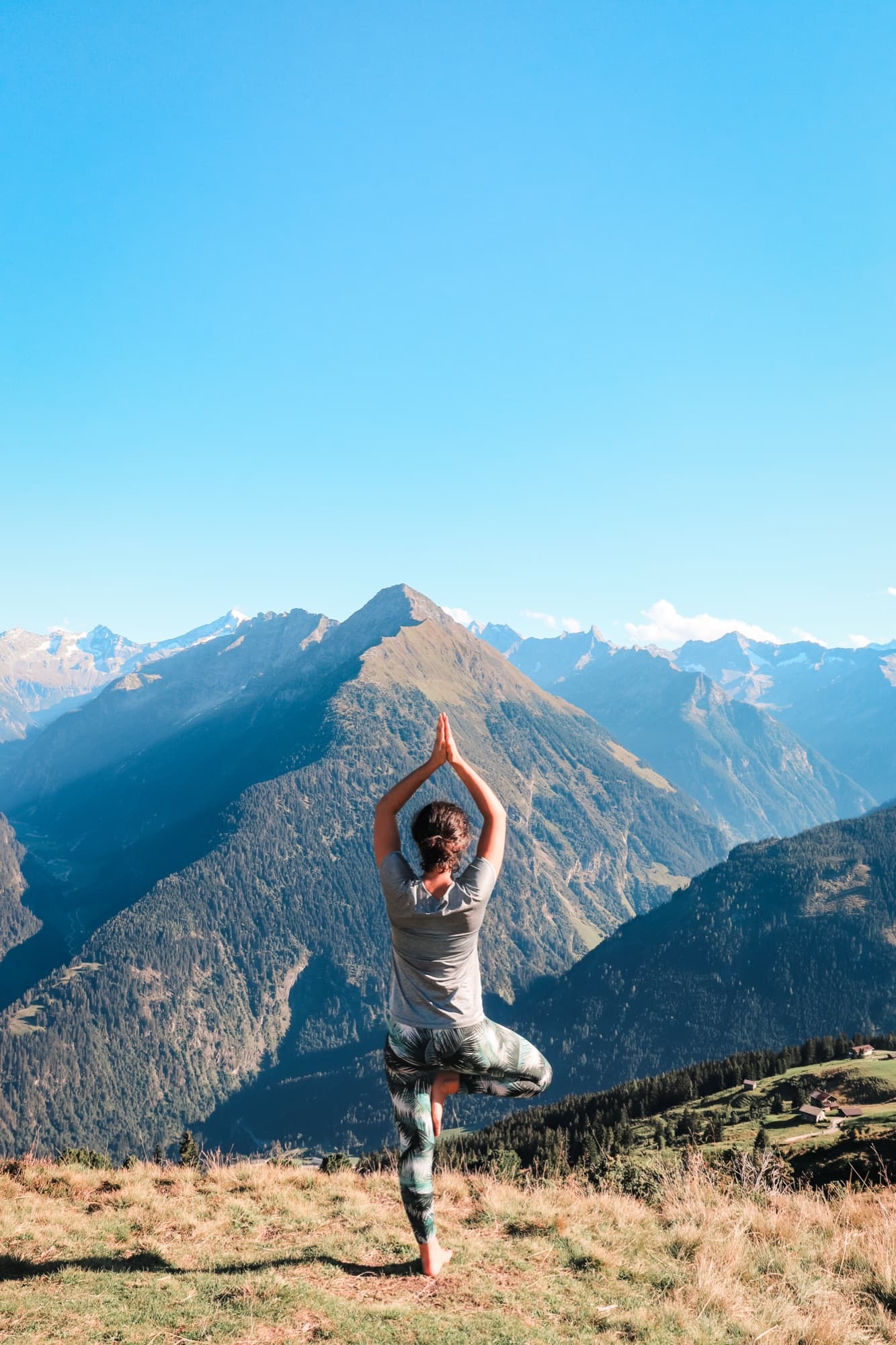 Sophie in der Baum-Pose auf einem Berggipfel beim Yogaretreat